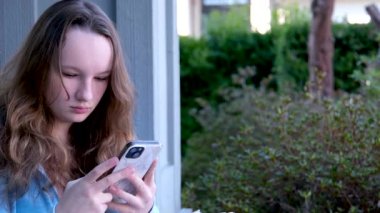 Genç ortadoğulu kız şehirde akıllı telefon kullanarak mutlu bir şekilde gülümsüyor. Yüksek kalite fotoğraf