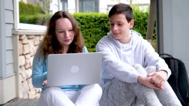 Oğlan, elinde dizüstü bilgisayarla gülen kız videolar seyrediyor ilginç videolar ilanlar çekiyor dersler veriyor, çocuklar sorunları çözüyorlar çocuklar birlikte çocukluk aşkı yaşıyorlar açık havada ergenlik çağındaki gençler.
