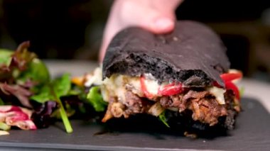 Mürekkepbalıklı, mürekkepli, çizburger sandviçli siyah ekmek. Pencere kenarında salata servis ediliyor. Lezzetli bulgogi, baharatlı bulgogi, ev yapımı, kalamar ekmekleri.