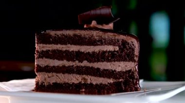 Kafe Prag 'da Dark Chocolate Cheesecake çikolatalı, çikolatalı, yakın çekimli, kremalı, siyah pastalı, beyaz bir tabakta servis edilen metin restoranı için güzel video reklamlı bir yer.