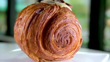 Lokantada lezzetli bir tatlı, beyaz bir tabakta yuvarlak kruvasan, ceviz ve kremalı pasta Vanilyalı Kouign Amann yuvarlak kruvasan, New York Roll, Moda Pastası 