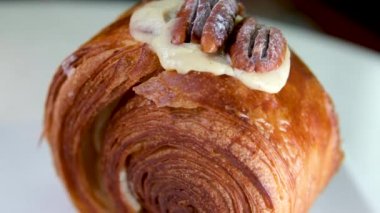 Lokantada lezzetli bir tatlı, beyaz bir tabakta yuvarlak kruvasan, ceviz ve kremalı pasta Vanilyalı Kouign Amann yuvarlak kruvasan, New York Roll, Moda Pastası 
