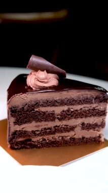 Kafe Prag 'da Dark Chocolate Cheesecake çikolatalı, çikolatalı, yakın çekimli, kremalı, siyah pastalı, beyaz bir tabakta servis edilen metin restoranı için güzel video reklamlı bir yer.