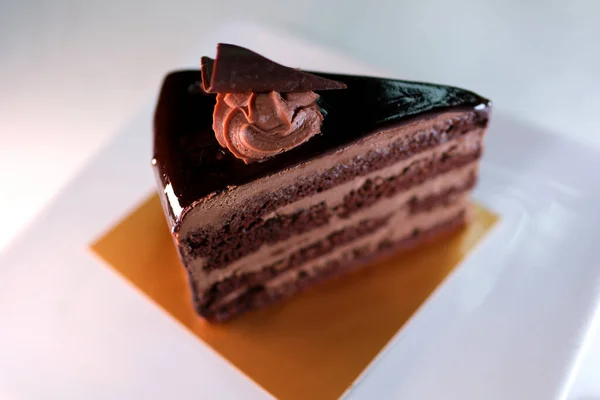 餐桌上放上一片美味的自制巧克力蛋糕 放在盘子里 三角形的黑巧克力和巧克力一起食用 — 图库照片