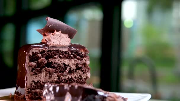セクション内のブラウニーチョコレートケーキの小さな美しい作品は 高価なレストランカフェのプレート上に立っています朝のカロリー砂糖光 — ストック動画