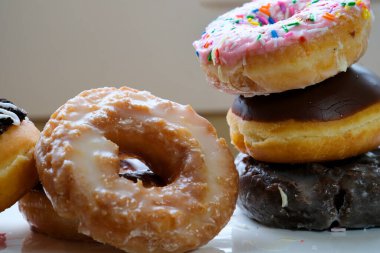 Kutudaki farklı tatlardan oluşan donutların olduğu masaya serpiştirilmiş lezzetli çöreklerden yakın çekim. Yüksek kalite 4k görüntü