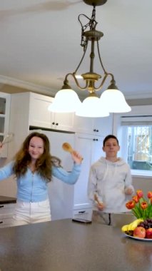 Erkek ve kız mutfakta kavga ediyor, dans ediyor, eğleniyor, birlikte vakit geçiriyor, suşi yiyor, kedi dansı yapıyor, müzik eşliğinde dans ediyor, mutfak aletleri sallıyor, evde tek başına eğleniyor, ebeveynleri yok.