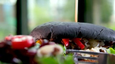 Bol peynirli büyük bir çizburger. Siyah tuğlalı arka planda bir çizburgerin stok fotoğrafı. El, siyah hamburgerden mürekkepli bir şiş çıkarır.