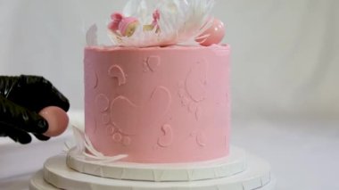 Aile için bir pasta süslemesi üzerinde melek kanatları ve pembe bebek bezli küçük bir çocuğun ayak izleri olan pembe pasta bir pasta yardımıyla çocuğun cinsiyetini nasıl öğrenilir?