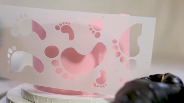 天使の翼の上に小さな子供の足跡とピンクのケーキを洗礼家族のためのケーキの装飾ピンクのおむつの女の子ケーキの助けを借りて子供の性別を見つける方法 — ストック動画