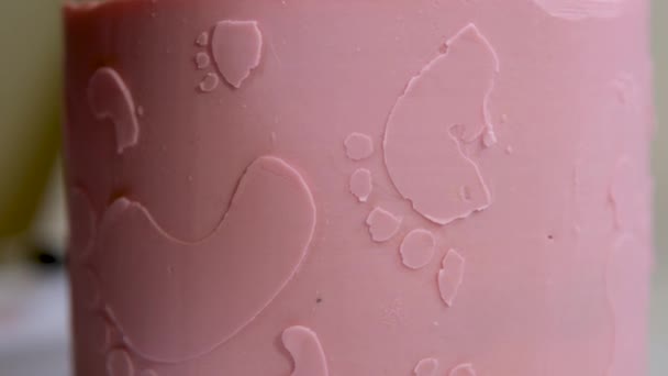 天使の翼の上に小さな子供の足跡とピンクのケーキを洗礼家族のためのケーキの装飾ピンクのおむつの女の子ケーキの助けを借りて子供の性別を見つける方法 — ストック動画