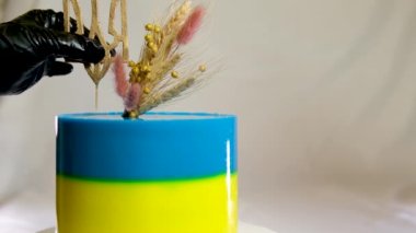 Ukrayna bayrağı şeklinde pasta. Sarı ve mavi katmanlı. Ukrayna arması, darı ve buğday başaklarıyla lezzetli bir pasta süslemesi.