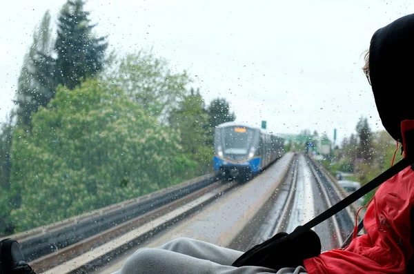 teenage boy sitting in windshield of sky train breaking rules resting out of control teenagers psychological problems trying to stand out from crowd danger safety equipment train is coming towards