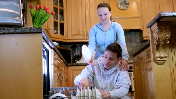 アメリカの若い人たちは 現代のキッチンで夕食後にきれいな口蓋を拭く一緒に家事をしています 幸せなカップル一緒に家事をしています 高品質4K映像 — ストック動画