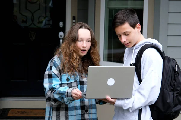 boy shows something on laptop of girl she corrects mistakes she smiles a briefcase on her shoulders classmates an excellent student and loser first relationship boy teenager clothes autumn spring