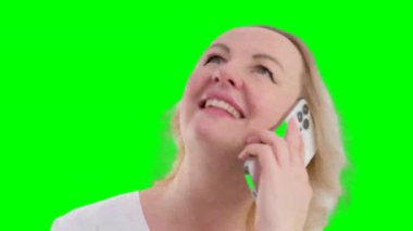 Güzel sarışın kadın cep telefonundan beyaz perdelerin önünde haber başındaki omuzlara gülümseyen bir telefon dinliyor. Yüksek kalite 4k görüntü