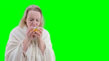 Evde elektrikli ısıtıcının yanında bir fincan sıcak çayla donan genç kadın çayımız çeşitli hastalıklardan uçup gidecek. 