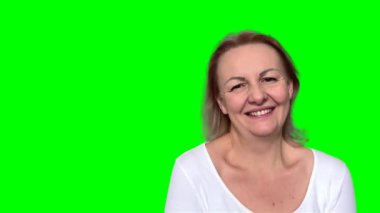 Canlı, pohpohlanmış, gözleri kıkırdayan bir kadın beyaz duvara yaslanırken bir anlık eğlenceyle mahvoldu. Mutlu doğal gülen genç kadın ağzını kapatıyor insan yüzü ifadeleri.