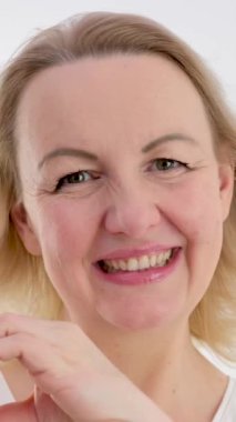 Kadın içten bir şekilde gülümsüyor elleriyle, beyaz bir arka planda gözlerini kısan bir kalbi gösteriyor. Aşk, sevgililer gününü bir ürün gibi hissettiriyor. 