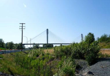 BC 'nin alt tarafındaki Fraser Nehri üzerindeki iskele köprüsü Kanada. Yakından bakınca büyük beyaz gerilmiş kablolar büyük bir köprü tutuyor. Coquitlam Limanı, Büyük Vancouver, British Columbia, Kanada 2023