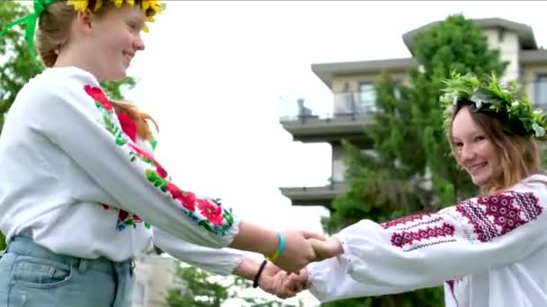 美しい若い女性が花輪を織っている女の子は庭で公園でおしゃべりを笑って歩いているひまわりの花や森の白い花の刺繍国のウクライナのシャツ花輪美しいVyshyvanka — ストック動画