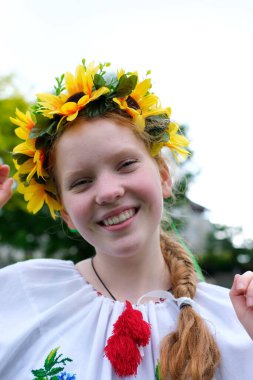 Genç, kızıl saçlı bir kız, açık havada, park bahçesinde güzel işlenmiş Ukrayna vyshyvanka gömleğiyle Ukrayna 'nın barış ve neşe dolu barış dolu barış ve neşe dolu barış dolu barış dolu zamanlarında.