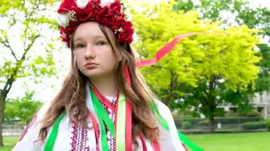 Güzel Ukraynalı genç bir kız parlak pembe kırmızı çiçekli kırmızı bir çelenk içinde saçları düzleştiren saçlarında kurdeleler ören Ukrayna 'da rüzgarın yumuşaklığı ve huzuru