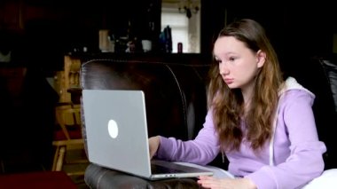 Görevleri çözme soruları internet üzerinden cevaplama elinde dizüstü bilgisayarla genç kızın ciddi sert yüzü koltuğa yaslanma problemleri çözme ev idaresi röportajında omuz silkme ve yan yana konuşma