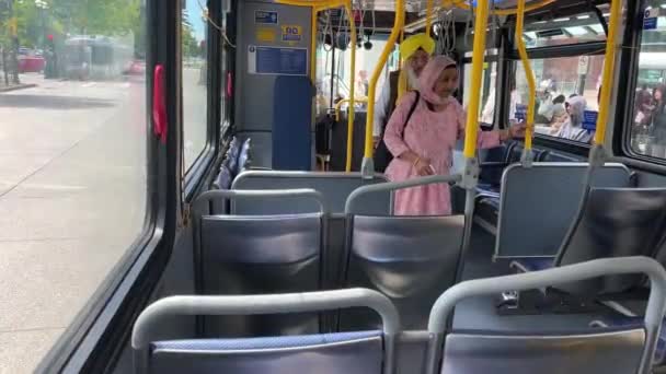 温哥华的公共汽车一对穿着特殊衣服的年迈的穆斯林夫妇拿着手杖坐在公共汽车上 坐在座位上排队在城市里转悠2023年加拿大人民的实际生活 — 图库视频影像