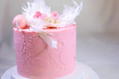 Lezzetli pembe bir pastanın dekorasyonu bir çocuğun doğumu için ve tatlının yanında vaftiz edilmiş bacak izleri için.