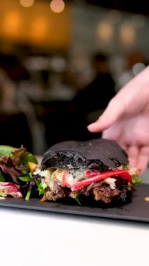 İştah açıcı bir burger yiyen genç bir adamın yakın çekimi. Yüksek kaliteli FullHD görüntüler