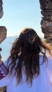 Ne yazık ki eski bir şatonun harabelerinde nakışlı bluz giyen Ukraynalı genç bir kız yok ve ne yazık ki etrafa bakıyor. Yüksek kalite 4k görüntü