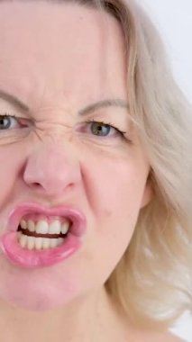Ağız aşağılayıcı, Yavaş Hareket... kız tatminsiz suratlar yapıyor... dudaklarıyla dişler farklı yönlere hareket ediyor... öfke saldırganlığı yaratıyor... sarışın bir kadının yakın çekim yüzü.