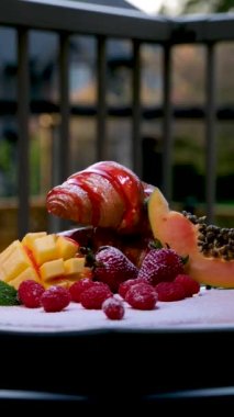 Lezzetli çilek şurubuyla serpilmiş kruvasan. Beyaz tabakta meyve yığını. Tatlı tabağı iştah açıcı.