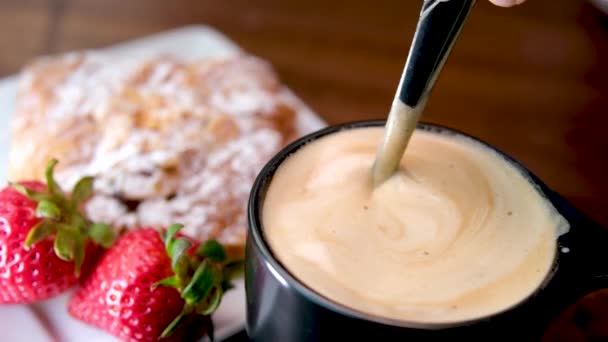 朝食に焼きたてのフランスクロワッサンを食べるラテカプチーノミルクとスプーン厚い泡のコーヒーと攪拌 — ストック動画