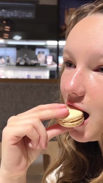 唇の上にモルを持つ10代の少女茶色の髪の女性は ゆっくりとそれをかむと喜びで吹くMakarunクローズアップを食べます 垂直ビデオ — ストック動画