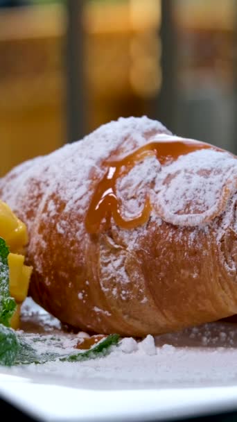 Menyiram Croissant Dengan Karamel Cair Atas Piring Putih Mangga Daun — Stok Video