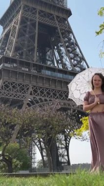 İhale yakın çekimi, metin için bir yer olan her reklam için kullanılabilir. Açılış şemsiyeli kız Eyfel Kulesi 'nden parlak yeşil bir ağacın arka planına doğru yürüyor.