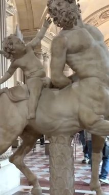 Louvre 'da sırtında bir melek olan bir Centaur heykeli. Orada bir sürü insan var, eğitici, 26.04.23 Paris Fransa. Yüksek kalite 4k görüntü
