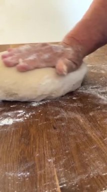 Yaşlı bir kadının yaşlı elleri hamuru yuvarlar ve bir şeyler pişirir ya da hamur köftelerini ya da hamur köftelerini ahşap bir yüzeyde kaynatır. Yüksek kalite 4k görüntü