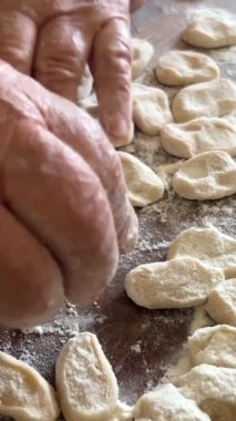  Hamur köftelerini heykeller ve ahşap bir masaya koyar, onlardan bir sürü vardır, unu iştah açıcıdırlar ve pişirilmeyi beklerler her hamur köftesi etle doludur, yuvarlaktır ve düzgünce el yapımıdır.