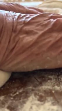 Yaşlı bir kadının yaşlı elleri hamuru yuvarlar ve bir şeyler pişirir ya da hamur köftelerini ya da hamur köftelerini ahşap bir yüzeyde kaynatır. Yüksek kalite 4k görüntü
