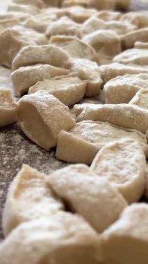 Yaşlı bir kadının yaşlı elleri hamuru yuvarlar ve bir şeyler pişirir ya da hamur köftelerini ya da hamur köftelerini ahşap bir yüzeyde kaynatır. Yüksek kalite 4k görüntü