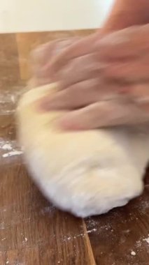 Yaşlı bir kadının yaşlı elleri hamuru yuvarlar ve bir şeyler pişirir ya da hamur köftelerini ya da hamur köftelerini ahşap bir yüzeyde kaynatır. Yüksek kalite 4k görüntü