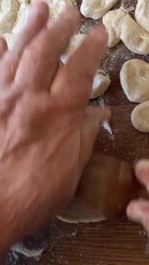 Büyükannem torunu için lezzetli börekler, turtalar ya da börekler hazırlar. Hamuru sallar, parçalara ayırır ve masanın üzerinde heykeller yapar. Üzerinde un serpiştirilmiş hamurlar vardır.