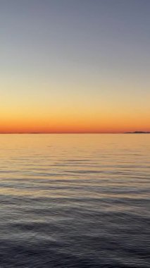 Deniz ve gökyüzünün arka planında gün batımı ve ufukta çok parlak kırmızı-turuncu renkli bir şerit sükunet ve dinlenme akşamı. 
