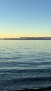 Deniz ve gökyüzünün arka planında gün batımı ve ufukta çok parlak kırmızı-turuncu renkli bir şerit sükunet ve dinlenme akşamı. 