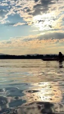 a teenage girl is kayaking at sunset in the Pacific Ocean, only the silhouette of Kayak and Paddles is visible she swims along a sunny path to the sea. a beautiful sky with small clouds