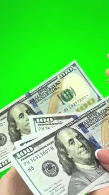  yeşil arkaplan rengi erkek elleri kadın ellerine 100 dolarlık banknotlar veriyor kadın her banknotu sayıyor orjinalliği dikkate alındığında başparmakları gösteriyor 
