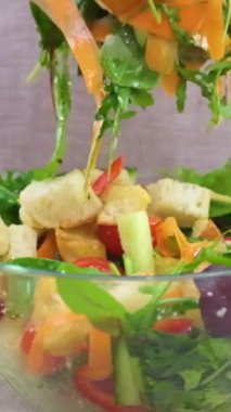 A woman mixes ingredients of vegetable salad in bowl. Close-up Mix ingredients of vegetarian salad Preparation of vegetable salad. slow motion video falling lettuce being mixed in glass plate carrots